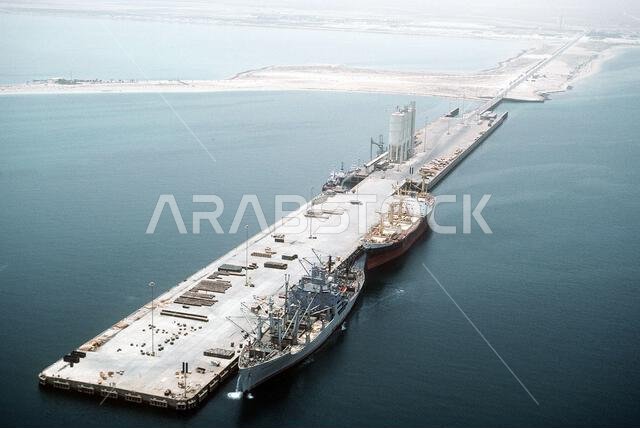 ترسو سفينة الشحن "كيب بون" (T-AK-5059)، المستأجرة من قبل قيادة النقل البحري العسكري، على رصيف الميناء مع فتح عنابر الشحن. ستحمل السفينة معدات وذخائر لإعادة نشرها في الولايات المتحدة في أعقاب عملية عاصفة الصحراء. ترسو سفينة تجارية خلف "كيب بون". العملية/السلسلة: عاصفة الصحراء. الدولة: المملكة العربية السعودية.