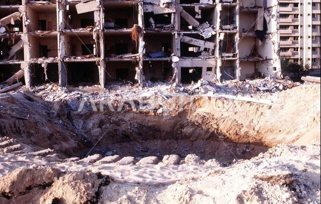 حفرة القنبلة أمام الجانب الشمالي المتضرر بشدة من المبنى المستهدف في مجمع أبراج الخبر. أسفر انفجار شاحنة وقود فجرها إرهابيون في تمام الساعة 2:55 مساءً بتوقيت شرق الولايات المتحدة، يوم الثلاثاء 25 يونيو 1996، خارج السياج الشمالي لمجمع أبراج الخبر بالقرب من قاعدة الملك عبد العزيز الجوية، عن مقتل 19 شخصًا وإصابة أكثر من 260 آخرين. كان المجمع يضم أفرادًا من القوات الأمريكية، وكان بمثابة مقر قيادة الجناح 4404 (المؤقت) في جنوب غرب آسيا. الموضوع: عملية/سلسلة: المراقبة الجنوبية