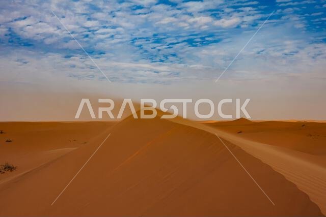 Sand blowing off the ridge of a sand dune in the desert, Saudi Arabia