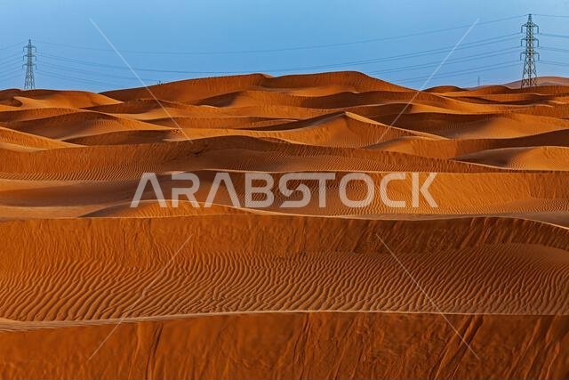 أبراج الكهرباء والكثبان الرملية في منظر صحراوي، المملكة العربية السعودية