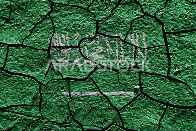 علم المملكة العربية السعودية على أرضية ذات ملمس طيني وشق جاف