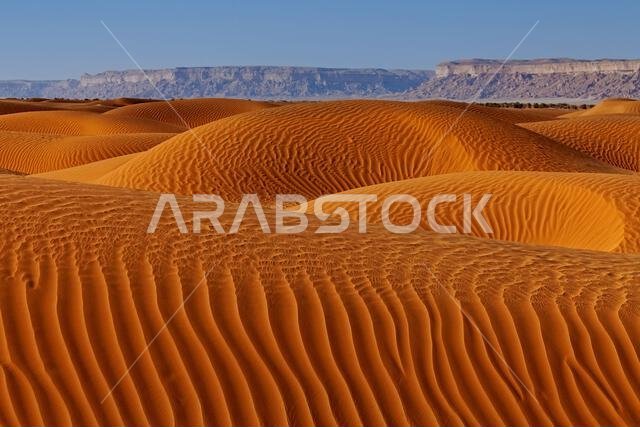 Desert landscape with ripped sand dunes with mountain backdrop, Saudi Arabia