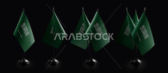 Small national flags of the Saudi Arabia on a black background.