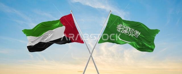two crossed flags Saudi Arabia and United Arab Emirates waving in wind at cloudy sky. Concept of relationship, dialog, travelling between two countrie