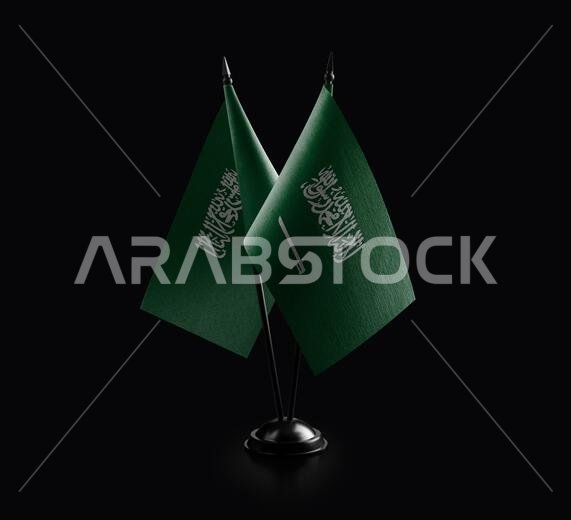 أعلام وطنية صغيرة للمملكة العربية السعودية على خلفية سوداء.