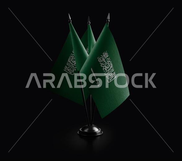 أعلام وطنية صغيرة للمملكة العربية السعودية على خلفية سوداء.