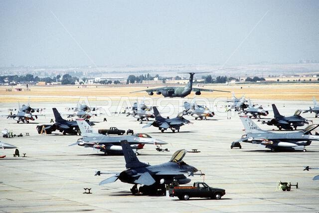 F-16C Fighting Falcon aircraft of the 401st Tactical Fighter Wing are parked on the flight line as a C-141B Starlifter aircraft taxis in the background. The aircraft are deploying to Saudi Arabia in support of Operation Desert Shield. Subject Operation/Series: DESERT SHIELD Base: Torrejon Air Base Country: Spain (ESP) F-16C Fighting Falcon aircraft of the 401st Tactical Fighter Wing are parked on the flight line as a C-141B Starlifter aircraft taxis in the background. The aircraft are deploying to Saudi Arabia in support of Operation Desert Shield. Subject Operation/Series: DESERT SHIELD Base: Torrejon Air Base Country: Spain (ESP)