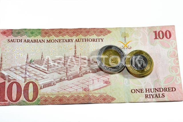 Reverse side of 100 SAR one hundred Saudi Arabia riyals cash money banknote features the prophet mosque in Medina with change of Saudi riyal coins 1 a