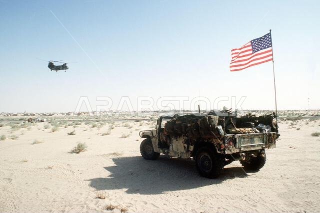 يرفرف العلم الأمريكي على مركبة هامفي (HMMWV) عالية الحركة من طراز M998 محملة بالإمدادات، أثناء توقفها في معسكر قاعدة خلال عملية درع الصحراء. العملية/السلسلة: درع الصحراء. الدولة: المملكة العربية السعودية.