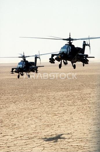 Two AH-64A Apache helicopters pass over the desert during Operation Desert Shield. Each helicopter is armed with a pair of 19-round launchers for 2.75-inch folding-fin aerial rockets; the helicopter at right is also carrying eight AGM-114 Hellfire missiles. Subject Operation/Series: DESERT SHIELD Country: Saudi Arabia (SAU) Two AH-64A Apache helicopters pass over the desert during Operation Desert Shield. Each helicopter is armed with a pair of 19-round launchers for 2.75-inch folding-fin aerial rockets; the helicopter at right is also carrying eight AGM-114 Hellfire missiles. Subject Operation/Series: DESERT SHIELD Country: Saudi Arabia (SAU)