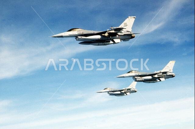 An air-to-air view of three F-16C Fighting Falcon aircraft of the 388th Tactical Fighter Wing en route to Saudi Arabia for Operation Desert Shield. Each aircraft is carrying external fuel tanks, AIM-9 Sidewinder missiles and an AN/ALQ-131 electronic countermeasures (ECM) pod. The center aircraft is also carrying a low altitude navigation, targeting infrared night (LANTIRN) navigation pod on the left side of its engine intake. Subject Operation/Series: DESERT SHIELD Country: Unknown