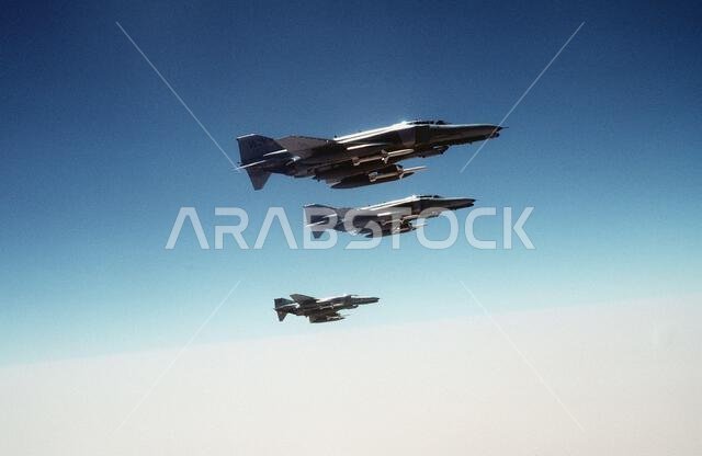 Three 35th Tactical Fighter Wing F-4G Phantom II aircraft pass over the Saudi desert while on a training flight during Operation Desert Shield. The aircraft are carrying external fuel tanks on their outboard wing pylons and AGM-88 HARM high-speed anti-radiation missiles on their inboard wing pylons. Subject Operation/Series: DESERT SHIELD Country: Saudi Arabia (SAU)