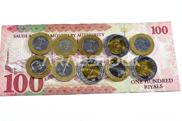 100 SAR one hundred Saudi Arabia riyals cash money banknote with pile of Saudi riyal coins 1 and 2 riyals features king Salman Bin AbdulAziz Al Saud a
