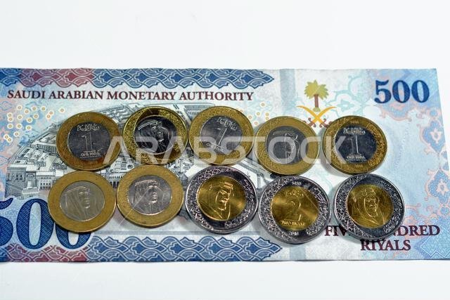 500 SAR five hundred Saudi Arabia riyals cash money banknote with pile of Saudi riyal coins 1 and 2 riyals features king Salman Bin AbdulAziz Al Saud