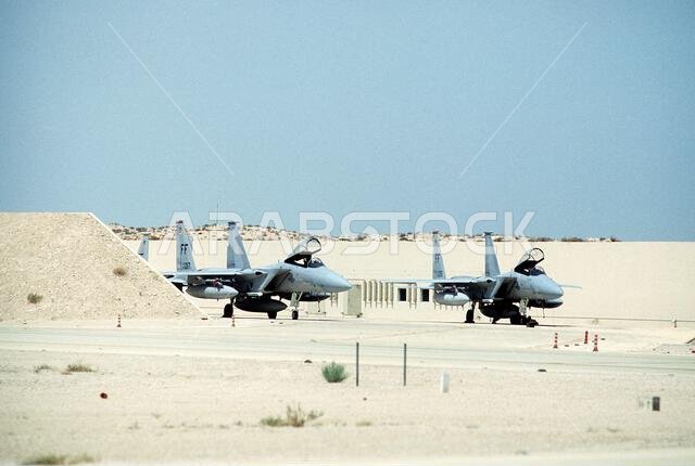 Two F-15C Eagle aircraft from the 1ST Tactical Fighter Wing (1ST TFW) sit parked on an apron during Operation Desert Shield. Subject Operation/Series: DESERT SHIELD Country: Saudi Arabia (SAU)