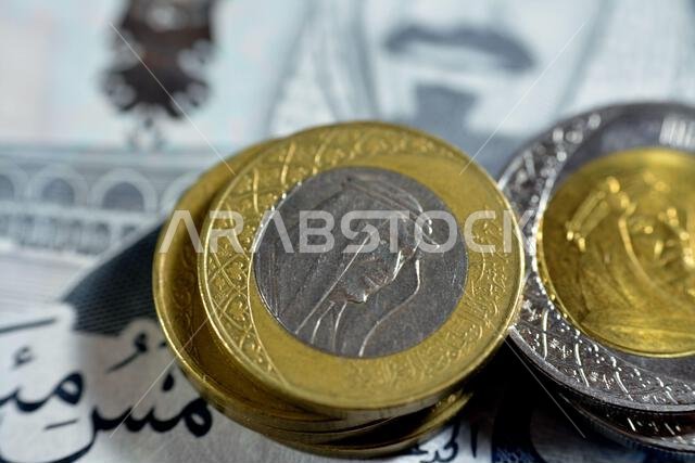 عملات معدنية سعودية من فئة 1 و2 ريال سعودي، تحمل صورة الملك سلمان والملك عبد العزيز آل سعود بشكل منفصل على فئة 500 ريال سعودي. عملات معدنية سعودية من فئة 1 و2 ريال سعودي، تحمل صورة الملك سلمان والملك عبد العزيز آل سعود بشكل منفصل على فئة 500 ريال سعودي.