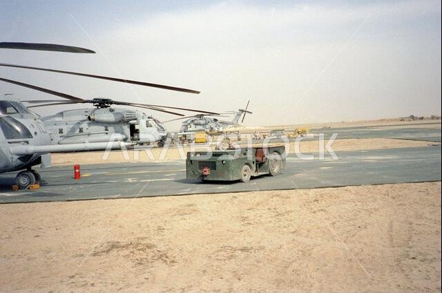 جرار سحب من طراز MD-3 يقف أمام مروحية من طراز CH-53E سوبر ستاليون متوقفة على مدرج مطار لونسم دوف الاستكشافي خلال عملية عاصفة الصحراء. الموضوع: عملية عاصفة الصحراء، الدولة: المملكة العربية السعودية. جرار سحب من طراز MD-3 يقف أمام مروحية من طراز CH-53E سوبر ستاليون متوقفة على مدرج مطار لونسم دوف الاستكشافي خلال عملية عاصفة الصحراء. الموضوع: عملية عاصفة الصحراء، الدولة: المملكة العربية السعودية.