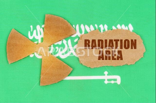 The concept of industry and radiation. On the flag of Saudi Arabia, the symbol of radioactivity and torn cardboard with the inscription - Radiation Ar The concept of industry and radiation. On the flag of Saudi Arabia, the symbol of radioactivity and torn cardboard with the inscription - Radiation Ar
