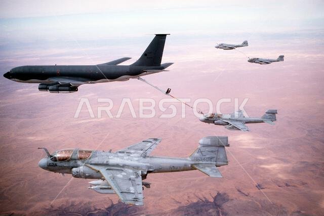 Two Tactical Electronic Warfare Squadron 130 (VAQ-130) EA-6B Prowler aircraft rendezvous with a KC-135E Stratotanker aircraft to refuel while en route to targets in Iraq during Operation Desert Storm. At upper right, a third Prowler aircraft is refueled by an Attack Squadron 75 (VA-75) A-6E Intruder aircraft carrying a "buddy store" external fuel tank. VAQ-130 and VA-75 are based aboard the aircraft carrier USS JOHN F. KENNEDY (CV-67). Subject Operation/Series: DESERT STORM Country: Saudi Arabia Two Tactical Electronic Warfare Squadron 130 (VAQ-130) EA-6B Prowler aircraft rendezvous with a KC-135E Stratotanker aircraft to refuel while en route to targets in Iraq during Operation Desert Storm. At upper right, a third Prowler aircraft is refueled by an Attack Squadron 75 (VA-75) A-6E Intruder aircraft carrying a "buddy store" external fuel tank. VAQ-130 and VA-75 are based aboard the aircraft carrier USS JOHN F. KENNEDY (CV-67). Subject Operation/Series: DESERT STORM Country: Saudi Arabia
