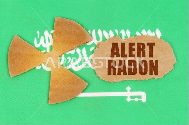 مفهوم الصناعة والإشعاع. على علم المملكة العربية السعودية، رمز النشاط الإشعاعي وقطعة من الورق المقوى الممزق مكتوب عليها: تحذير - رادون مفهوم الصناعة والإشعاع. على علم المملكة العربية السعودية، رمز النشاط الإشعاعي وقطعة من الورق المقوى الممزق مكتوب عليها: تحذير - رادون