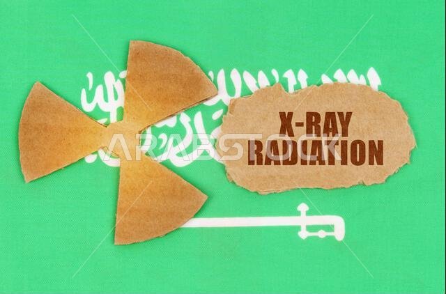 مفهوم الصناعة والإشعاع. على علم المملكة العربية السعودية، رمز النشاط الإشعاعي وقطعة من الورق المقوى الممزق مكتوب عليها: إشعاع الأشعة السينية مفهوم الصناعة والإشعاع. على علم المملكة العربية السعودية، رمز النشاط الإشعاعي وقطعة من الورق المقوى الممزق مكتوب عليها: إشعاع الأشعة السينية