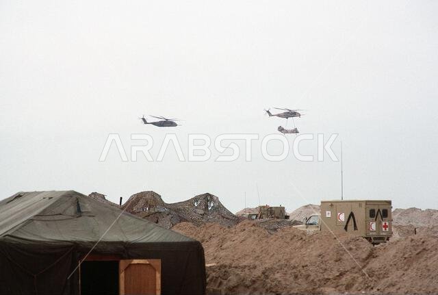 A CH-53E Super Stallion helicopter airlifts a CH-46 Sea Knight helicopter as another CH-53E follows behind. The helicopters have just taken off after a supply delivery during Operation Desert Storm. Subject Operation/Series: DESERT STORM Country: Saudi Arabia (SAU)
