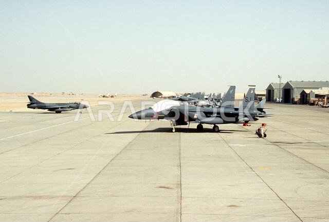 F-15E Eagle aircraft of the 336th Tactical Fighter Squadron are parked on the flight line during Operation Desert Shield. An FGA-9 Hunter aircraft is parked on the left. Subject Operation/Series: DESERT SHIELD Country: Saudi Arabia (SAU)