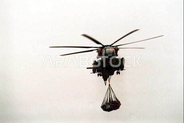 وصلت مروحية من طراز CH-53E سوبر ستاليون فوق مجمع الكتيبة البحرية المتنقلة الخامسة للإنشاءات (NMCB-5) محملة بالإمدادات. تتواجد الكتيبة في شمال المملكة العربية السعودية لتقديم الدعم الهندسي لقوات التحالف خلال عملية عاصفة الصحراء. الموضوع: عملية عاصفة الصحراء، الدولة: المملكة العربية السعودية.