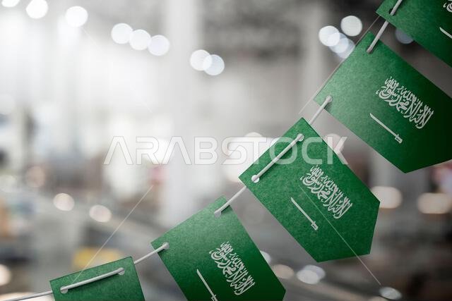 A garland of Saudi Arabia national flags on an abstract blurred background.