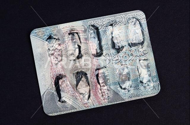 Medicine and business concept. On the blister with pills, the image of the banknote of Saudi Arabia is applied.