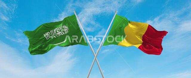 علمان متقاطعان لمالي والسعودية يرفرفان في مهب الريح تحت سماء ملبدة بالغيوم. يرمزان إلى مفهوم العلاقة والحوار والسفر بين البلدين. رسم توضيحي ثلاثي الأبعاد.