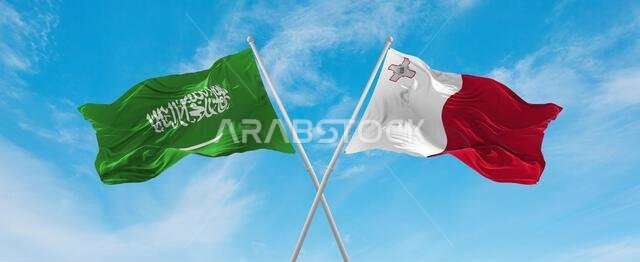 علمان متقاطعان، علم مالطا وعلم السعودية، يرفرفان في مهب الريح تحت سماء ملبدة بالغيوم. يرمز هذا العمل الفني إلى مفهوم العلاقة والحوار والسفر بين البلدين. رسم توضيحي ثلاثي الأبعاد.