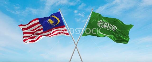 علمان متقاطعان، علم السعودية وعلم ماليزيا، يرفرفان في مهب الريح تحت سماء ملبدة بالغيوم. يرمز هذا إلى مفهوم العلاقة والحوار والسفر بين البلدين. رسم توضيحي ثلاثي الأبعاد.