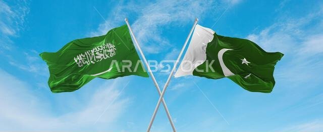 علمان متقاطعان، علم باكستان وعلم السعودية، يرفرفان في مهب الريح تحت سماء ملبدة بالغيوم. يرمز هذا إلى مفهوم العلاقة والحوار والسفر بين البلدين. رسم توضيحي ثلاثي الأبعاد.