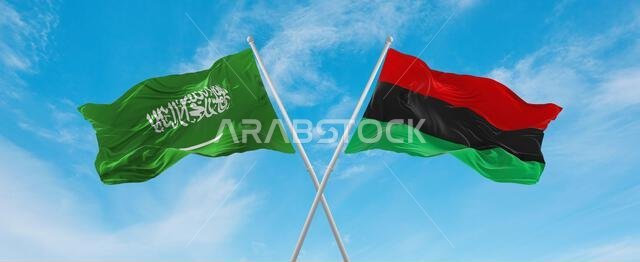 علمان متقاطعان، علم عموم أفريقيا وعلم السعودية، يرفرفان في مهب الريح تحت سماء ملبدة بالغيوم. يرمزان إلى مفهوم العلاقة والحوار والسفر بين البلدين. رسم توضيحي ثلاثي الأبعاد