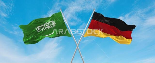 علمان متقاطعان، علم جمهورية ألمانيا الاتحادية وعلم المملكة العربية السعودية، يرفرفان في مهب الريح تحت سماء ملبدة بالغيوم. يرمز هذا إلى مفهوم العلاقة والحوار والسفر بين دولتين.