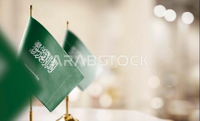 أعلام صغيرة للمملكة العربية السعودية على خلفية ضبابية مجردة.