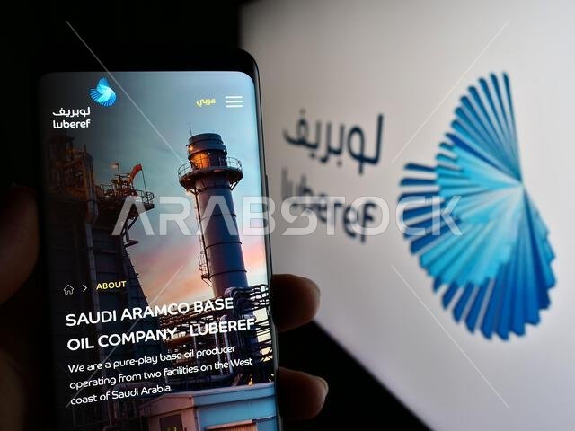 Person holding mobile phone with website of Saudi Arabian base oil company Luberef on screen in front of logo. Focus on center of phone display.