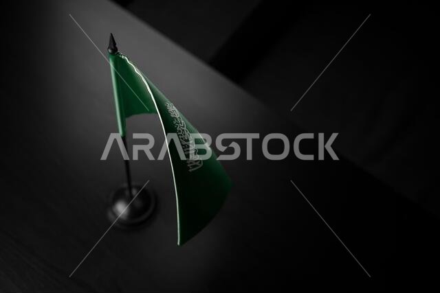 Small national flag of the Saudi Arabia on a black background.