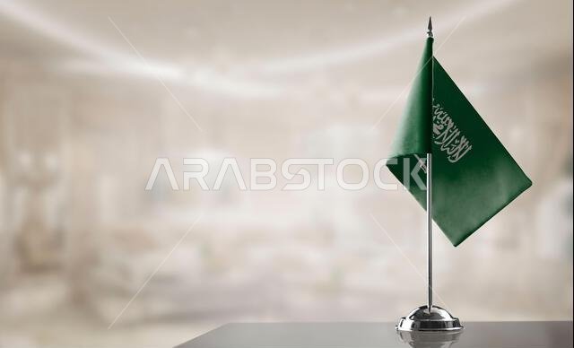 A small Saudi Arabia flag on an abstract blurry background.