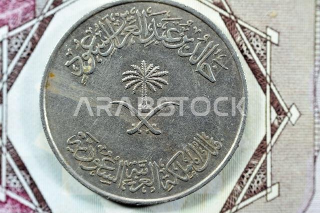 سيوف متقاطعة ونخلة في وسط وجه العملة السعودية القديمة، مئة هللة، ريال سعودي واحد، ١٣٩٦ هـ.