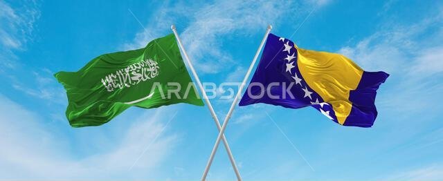 علمان متقاطعان، علم البوسنة والهرسك وعلم السعودية، يرفرفان في مهب الريح تحت سماء ملبدة بالغيوم. يرمز هذا إلى مفهوم العلاقة والحوار والسفر بين البلدين.