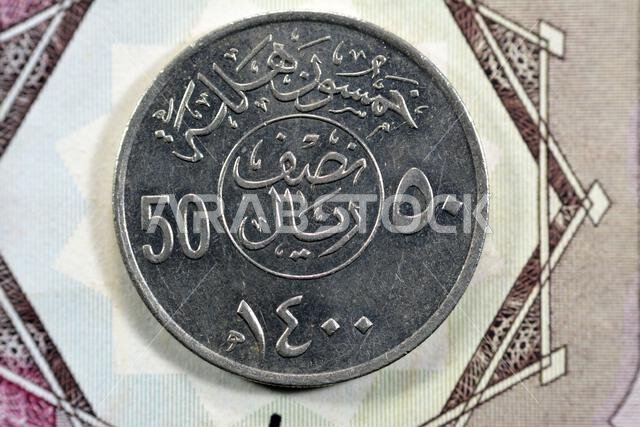 الوجه الخلفي لعملة نصف ريال سعودية قديمة من فئة 50 هللة، ترجمة (50 هللة، سلسلة عملات نصف ريال، 1400 هـ)، نقش فوق الكتابة داخل دائرة تقسم حرف v