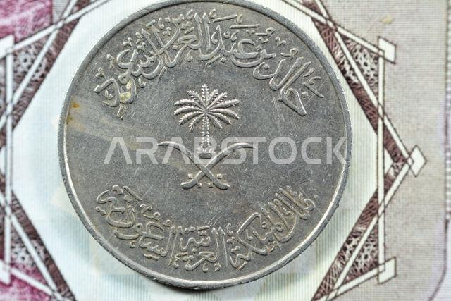 Crossed swords and palm tree at center of obverse side of old Saudi Arabia One hundred Halalah 100 halalas One Saudi Riyal coin 1396 AH, Translation o Crossed swords and palm tree at center of obverse side of old Saudi Arabia One hundred Halalah 100 halalas One Saudi Riyal coin 1396 AH, Translation o