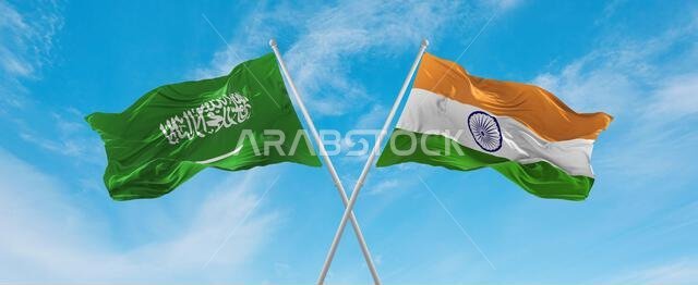 علمان متقاطعان، علم الهند وعلم السعودية، يرفرفان في مهب الريح تحت سماء ملبدة بالغيوم. يرمز هذا العمل الفني إلى مفهوم العلاقة والحوار والسفر بين البلدين. رسم توضيحي ثلاثي الأبعاد.