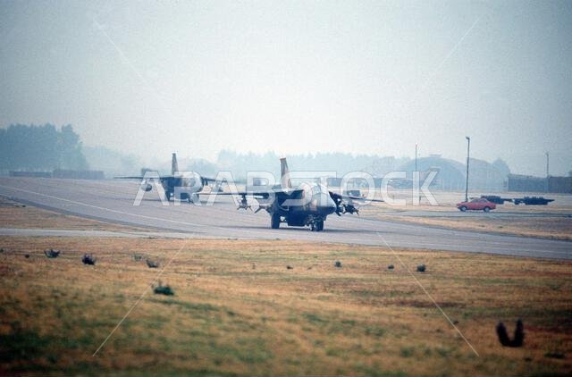 F-111F aircraft of the 48th Tactical Fighter Wing taxi to the flight line as they prepare to depart for Saudi Arabia in support of Operation Desert Shield. The lead F-111F is equipped with GBU-15 glide bombs on the inboard wing pylons and laser-guided bombs on the outboard pylons. Subject Operation/Series: DESERT SHIELD Base: Raf Mildenhall Country: Great Britain / England (GBR) F-111F aircraft of the 48th Tactical Fighter Wing taxi to the flight line as they prepare to depart for Saudi Arabia in support of Operation Desert Shield. The lead F-111F is equipped with GBU-15 glide bombs on the inboard wing pylons and laser-guided bombs on the outboard pylons. Subject Operation/Series: DESERT SHIELD Base: Raf Mildenhall Country: Great Britain / England (GBR)