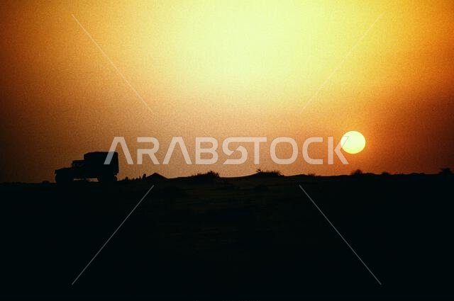 مركبة M-998 متعددة الأغراض عالية الحركة ذات عجلات، تابعة للكتيبة الثالثة، الفوج التاسع من مشاة البحرية، تظهر كظلالها مع شروق الشمس خلال عملية درع الصحراء. العملية/السلسلة: درع الصحراء. الدولة: المملكة العربية السعودية.