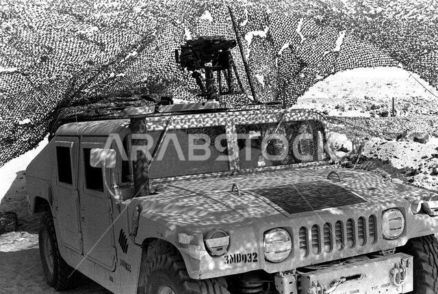 An M1038 High-Mobility Multipurpose Wheeled Vehicle (HMMWV) with a Mark 19 automatic grenade launcher mounted on its roof sits beneath a camouflage net at the 1ST Battalion, 5th Marines, combat operations center (COC) during Operation Desert Shield.. Subject Operation/Series: DESERT SHIELD Country: Saudi Arabia(SAU)