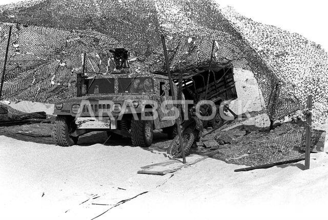 An M1038 High-Mobility Multipurpose Wheeled Vehicle (HMMWV) and a motorcycle sit beneath a camouflage net at the 1ST Battalion, 5th Marines, combat operations center (COC) during Operation Desert Shield. A Mark 19 automatic grenade launcher is mounted on the roof of the HHMMWV.. Subject Operation/Series: DESERT SHIELD Country: Saudi Arabia(SAU) An M1038 High-Mobility Multipurpose Wheeled Vehicle (HMMWV) and a motorcycle sit beneath a camouflage net at the 1ST Battalion, 5th Marines, combat operations center (COC) during Operation Desert Shield. A Mark 19 automatic grenade launcher is mounted on the roof of the HHMMWV.. Subject Operation/Series: DESERT SHIELD Country: Saudi Arabia(SAU)