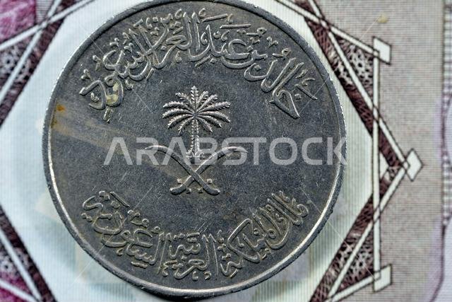 Crossed swords and palm tree at center of obverse side of old Saudi Arabia One hundred Halalah 100 halalas One Saudi Riyal coin 1396 AH, Translation o Crossed swords and palm tree at center of obverse side of old Saudi Arabia One hundred Halalah 100 halalas One Saudi Riyal coin 1396 AH, Translation o